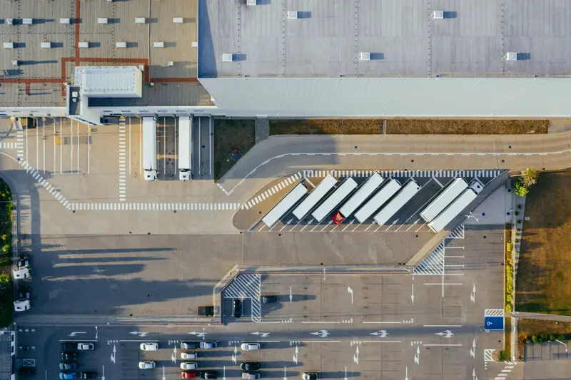 Vista aérea de um centro de distribuição com carretas estacionadas no pátio e docas de carga