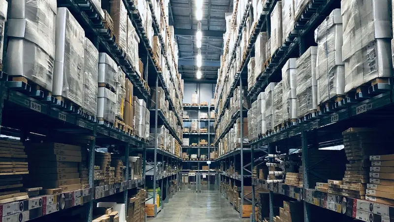 Corredor de um galpão com estantes altas dos dois lados