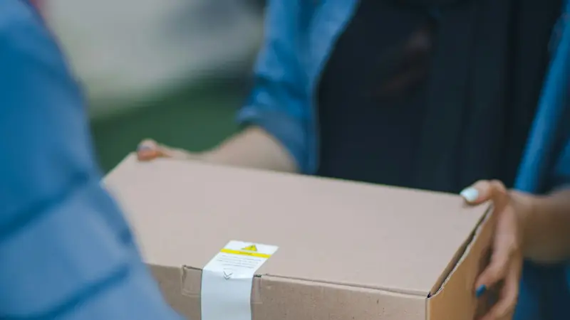 Uma pessoa entrega uma caixa de papelão nas mãos de outra