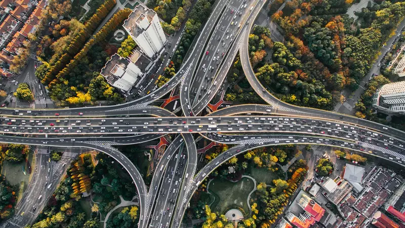 Trevo rodoviário visto de cima, com viadutos cruzados e carros em várias pistas